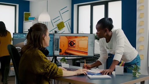 多民族女性游戏设计师看电脑双显示器在工作室项目办公室一起工作